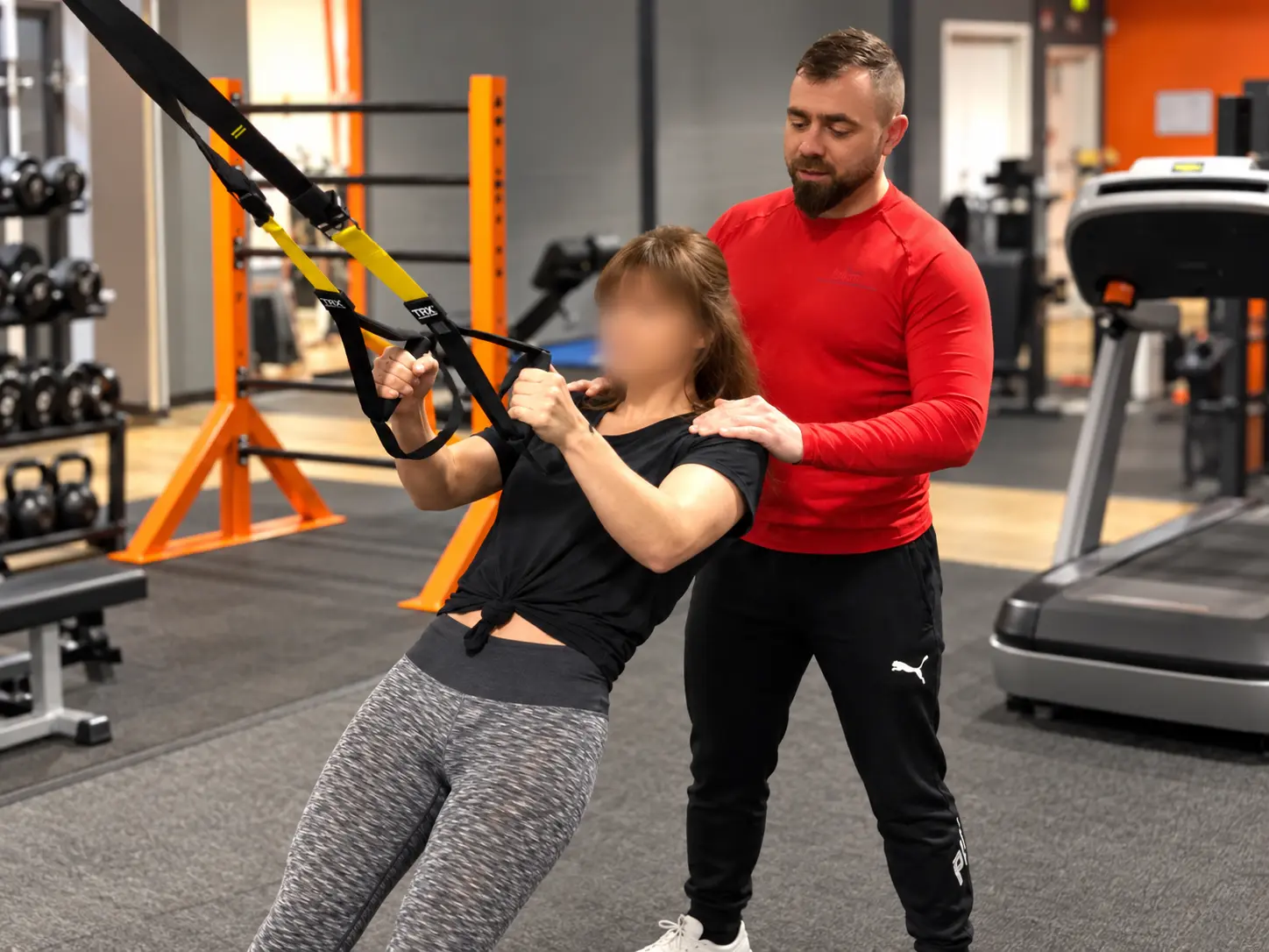 Ludovic Peene coaching a client during a TRX suspension-training exercise, providing hands-on guidance and movement correction.